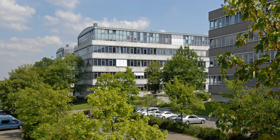 Geschossbauten am Campus Süd. Im Vordergrund grüne Laubbäume.